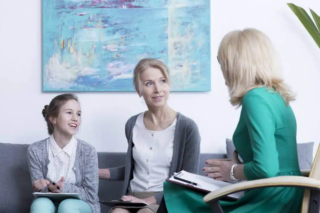 Happy mother with smiling teenage daughter at psychologist's