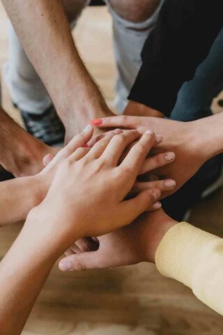 photo of participants in therapy putting their hands together as they discuss the benefits of teen group therapy