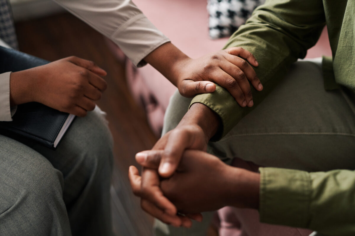 female psychologist keeping hand of wrist of male patient